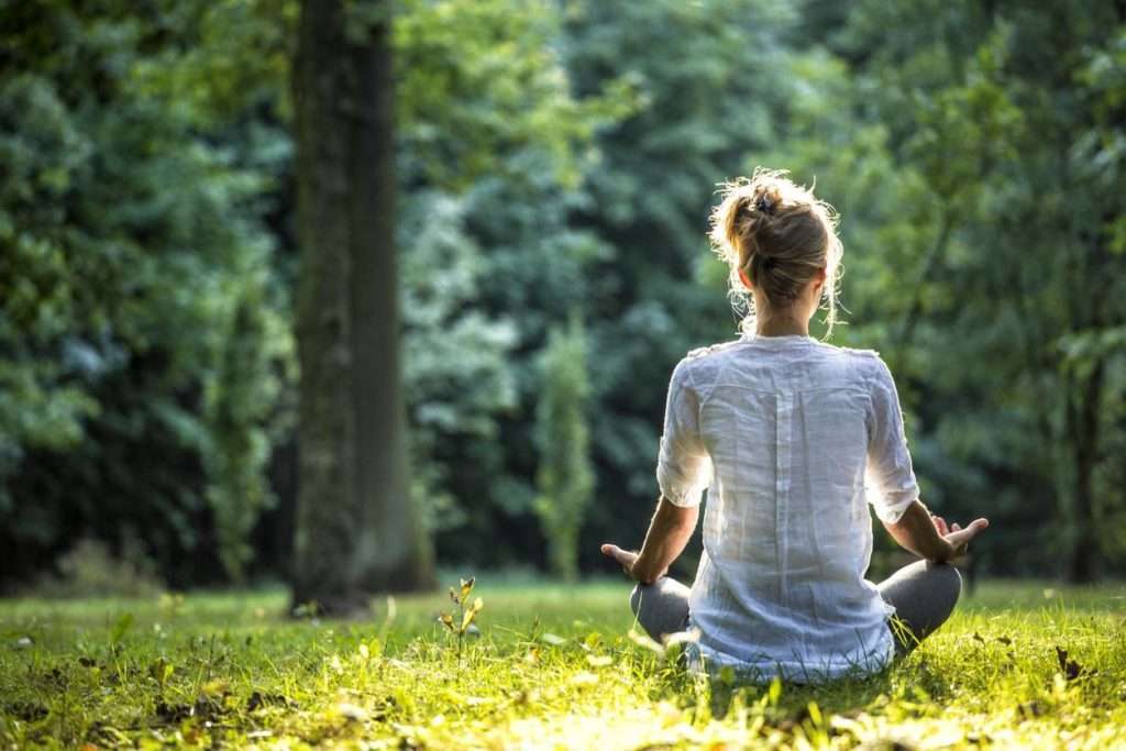 Personne méditant assise dans un parc